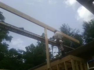 Carpenter setting a ridge beam over a new addition frame — Ice Dam Removal by Roofing Brothers in Columbiaville