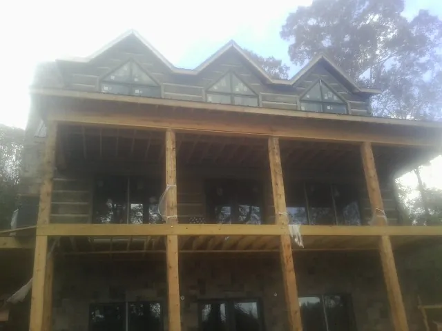 Dormers and porch framing on a large log home under construction — Roof Coating work by our crew in Columbiaville